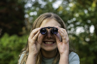 Young girl looks through binoculars 