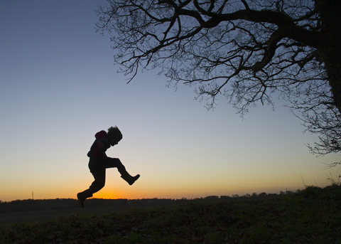 A silhouette of a child playing outdoors at sunset, The Wildlife Trusts