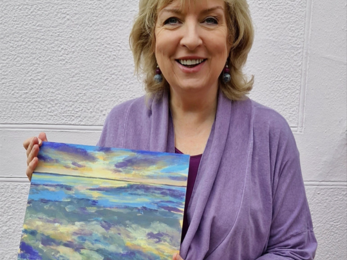 Pearl stands holding her sunset artwork.