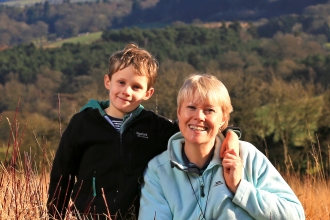 Kati and her son sat in a field with woods in background