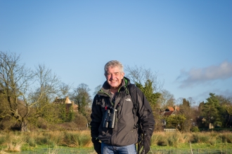 Tony stands in a wetland with his dogs