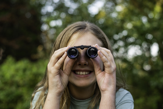 Young girl looks through binoculars