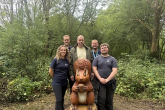 Team stood by wooden carved sculpture in Langdon Nature Discovery Park