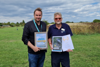 Peter Dimmick with Rich Yates, holding his certificate and awards