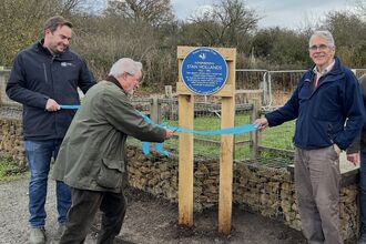 A ribbon being cut in front of a blue plaque