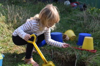 child digging in grass and mud
