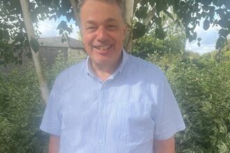 Man stood smiling in front of tree