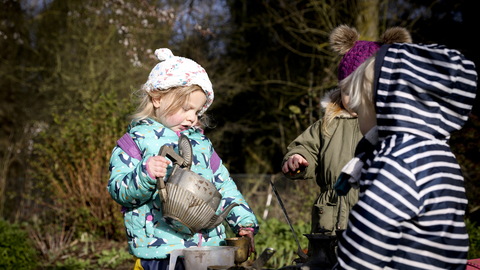 Three children in mud kitchen outdoors