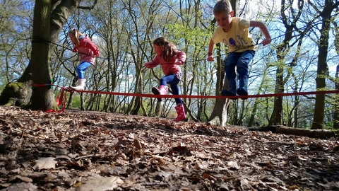 children on a slackline in spring forest