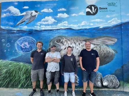 The Essex Wildlife Trust Marine and Coastal Recovery Team alongside artist Dave Gnash, in front of a marine mural