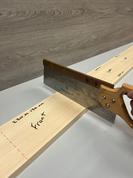 Using a saw to cut through wooden plank.