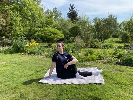 Woman in yoga pose surrounded by trees and grass in nature