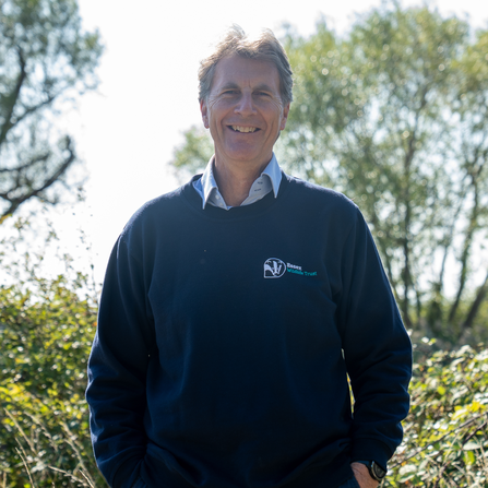 Man stood with trees in background, wearing a Essex Wildlife Trust jumper
