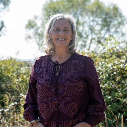 Woman stood in front of hedgerow 