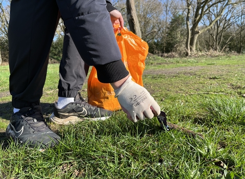 Someone bending down to pick up litter and holding a bag